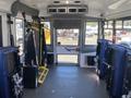 Interior view of a 2020 Chevrolet Express showing seats along the sides and safety equipment mounted on the walls with a clear view toward the front door