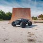 A black Arrma 1/5 Outcast 8S EXB 4X4 roller brushless stunt truck with large tires positioned in front of a ramp