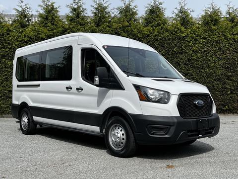 A 2022 Ford Transit van with a white exterior and black accents, featuring large windows and a streamlined front design