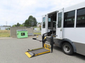A 2020 Chevrolet Express shuttle bus with a wheelchair lift extended from the side entrance