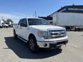 A white 2014 Ford F-150 pickup truck with a chrome grille and alloy wheels parked in a lot
