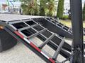 A 1998 Freightliner FL80 with a loading ramp featuring metal supports and a flatbed design