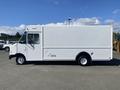 A white 2012 Ford Econoline van with a boxy shape and large side windows parked on a lot