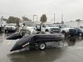 A black 2009 ShoreLandr ANDER boat with a motor on a trailer positioned in a parking lot with other vehicles around