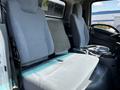 Interior view of a 2016 Isuzu NPR showing two upholstered front seats and a foldable rear bench seat designed for passenger comfort and utility