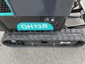 2024 AGT Industrial Green QH13R Mini Excavator showing the track and part of the body with a turquoise accent and model number QH13R prominently displayed