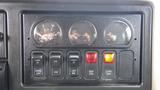 Dashboard control panel of a 2012 International 7400 featuring gauges for air pressure and multiple switches for vehicle functions