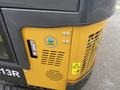A close-up of a 2024 AGT Industrial H13R Mini Excavator featuring its engine compartment with a yellow panel and safety stickers