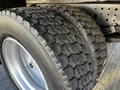 Close-up of two rugged tires of a 2014 Mitsubishi Fuso FE showcasing deep treads and a metal rim with a silver finish