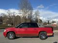 A red 2011 Chevrolet Avalanche with a gold trim and black accents on the sides is parked facing left with chrome wheels