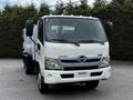 A white 2014 Hino 195 truck with a cab-over design featuring a large windshield and chrome grille with the Hino logo prominently displayed