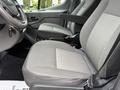The interior of a 2022 Ford Transit showing two front seats with gray fabric and armrests along with the steering wheel and controls visible