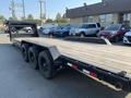 A 2020 Load Trail 28 Foot Gooseneck trailer featuring a wooden deck and three black wheels with a diamond plate fender