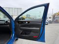 A blue 2021 Kia Forte with an open driver side door showing the interior features and door panel detail