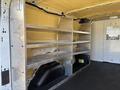Interior of a 2016 Ford Transit featuring metal shelving units on one side and storage space underneath without any contents visible