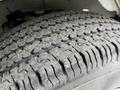 Close-up of a treaded tire on a 2023 GMC Savana showcasing deep grooves and a rugged surface designed for grip and durability