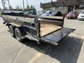 A black Southland SL716-20K dump trailer with dual axles and an open rear gate revealing a dirt load in the cargo area