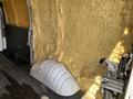 A 2009 Chevrolet Express interior with yellow foam insulation on the walls and a white wheel well cover on the floor