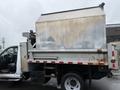 A 2011 Dodge Ram 5500 with a large metal dump bed in the back and an open driver's side door