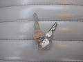 A set of keys including a key fob with a diamond-shaped design and two silver keys, placed on a light-colored textured surface