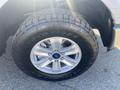 A close-up of a silver alloy wheel with a blue Ford logo mounted on a large Toyo tire designed for off-road use. The tread pattern is prominently displayed.