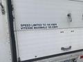 A white 2012 Ford Econoline van with a sign stating speed is limited to 105 KM/H on the rear door