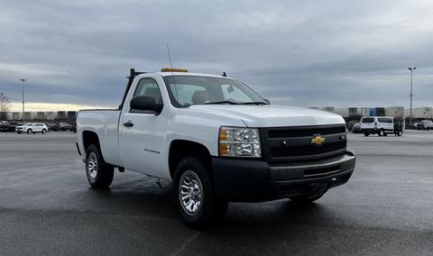 A 2013 Chevrolet Silverado 1500 pickup truck with a white exterior and a black front grille, featuring chrome wheels and a light on the cab roof