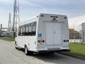A white 2010 Ford Econoline bus with a wheelchair accessibility symbol parked with rear doors visible