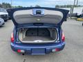 A blue 2007 Chrysler PT Cruiser with its rear hatch open displaying a spacious cargo area with a flat floor and foldable rear seats