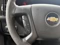 A close-up of the steering wheel of a 2020 Chevrolet Express featuring control buttons for cruise and audio functions with the Chevrolet logo in the center