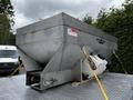 A silver metal tank mounted on a flatbed trailer with warning labels and secured by straps