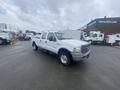 A white 2005 Ford F-350 SD with a crew cab and dual rear wheels parked on a lot showcasing its large size and sturdy build