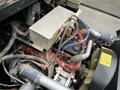 An exposed engine compartment of a 2015 Spartan School Bus showing various components including hoses, pipes, and a radiator reservoir