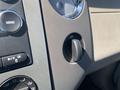 Close-up of the dashboard controls in a 2013 Ford Expedition showing knobs for menu and audio settings as well as a 12V power outlet