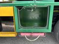 A green storage compartment attached to a truck showing no items inside with a pink container visible beneath it
