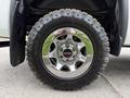 A close-up of a 2016 GMC Sierra 1500 wheel featuring a shiny chrome rim and a rugged Goodyear Wrangler tire with aggressive tread patterns