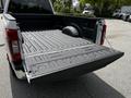 A 2020 Ford F-350 Super Duty with an open truck bed showing its textured surface and a spare tire stored in the side compartment