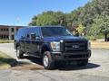 A 2014 Ford F-250 SD with a dark blue exterior and a truck bed cap parked on a paved surface