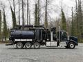 A 2018 Kenworth T800 truck outfitted with a large black vacuum tank and hoses attached to the top and sides