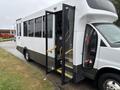 A 2020 Chevrolet Express bus with an open door and yellow steps leading inside, featuring multiple large windows on the side
