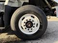Close-up of a 2011 International 7500 truck's tire and wheel assembly showing a white rim with black lug nuts and a visible tire tread pattern