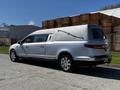 A silver 2013 Lincoln MKT hearse with a long body and a sleek design featuring a curved roof and a side-mounted handle