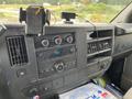 A 2014 GMC Savana dashboard featuring stereo controls a digital display and various knobs and buttons for vehicle settings
