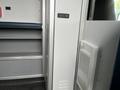 Interior view of a 2016 Chevrolet Express showing part of the rear door and storage compartments with a white air conditioning unit