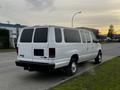 A white 2011 Ford Econoline van with tinted windows and chrome wheels parked on a street