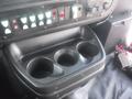 A console with three cup holders and various control buttons in a 2016 Chevrolet Express vehicle