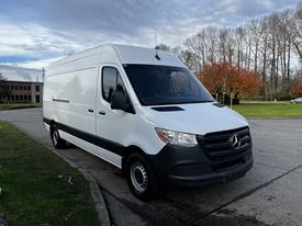 A 2022 Mercedes-Benz Sprinter van in white with a black lower section parked on a street