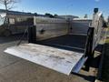 A 2014 Mitsubishi Fuso FE truck with an open flatbed and a raised loading ramp in the foreground