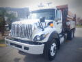 A 2016 International WorkStar 7500 truck with a white body and prominent front grille features visible headlights and a red dump bed attached to the rear