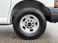 A close-up of a 2014 GMC Savana wheel featuring a shiny silver rim with the GMC logo and a black tire with tread visible